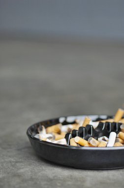 Full ashtray of cigarettes on table clipart