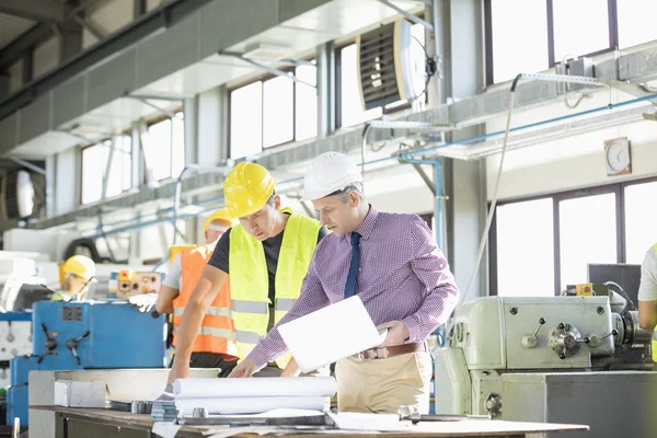 Arquitecto y trabajador manual leyendo plano — Foto de Stock