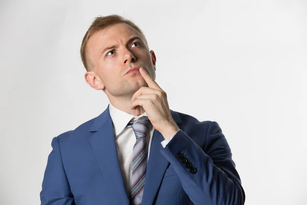Businessman with finger on face thinking — Stock Photo, Image