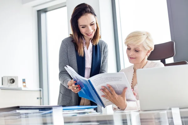 Lachende zakenvrouwen lezen boek in kantoor — Stockfoto