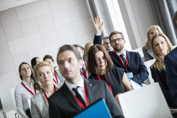 Businessman raising hand during seminar — Stock Photo, Image