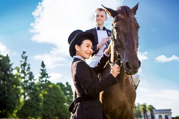 Woman standing by man sitting on horse — Stock Photo, Image