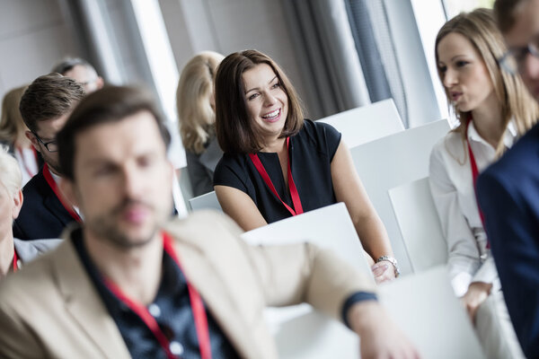 businesswoman sitting with colleagues in seminar hall 