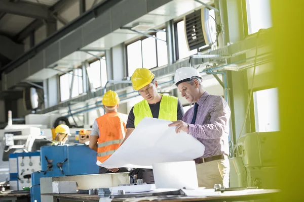 Arquitecto y trabajador manual leyendo plano — Foto de Stock