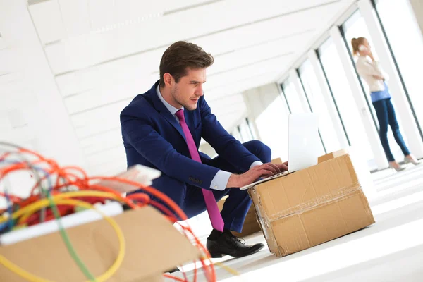 Businessman using laptop on cardboard box — Stock Photo, Image