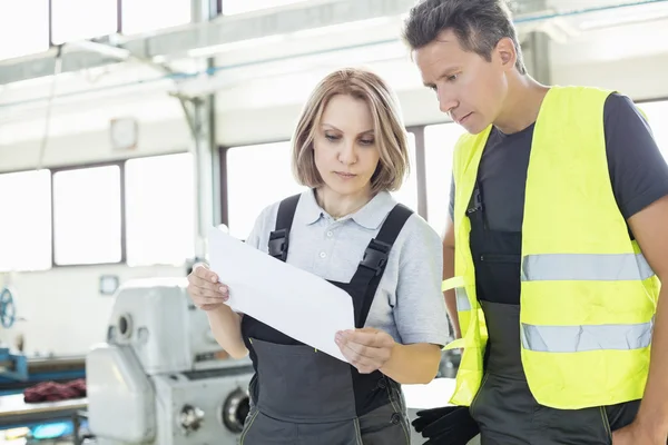 Manual workers examining paper in industry — Stock Photo, Image