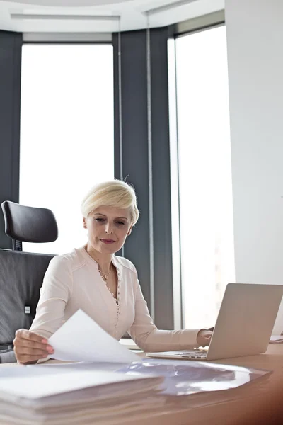 Mujer de negocios con documento y portátil en el escritorio — Foto de Stock