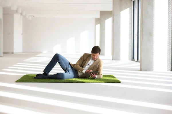 Geschäftsmann liegt mit digitalem Tablet auf Rasen — Stockfoto