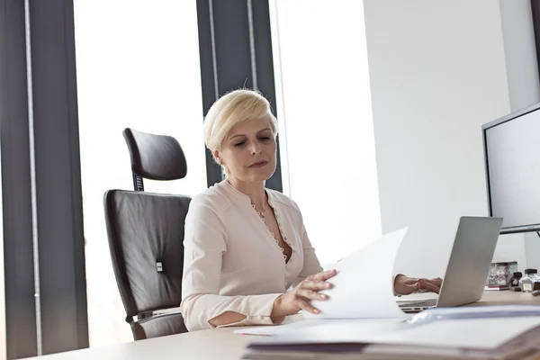 Geschäftsfrau liest Dokument am Schreibtisch im Büro — Stockfoto