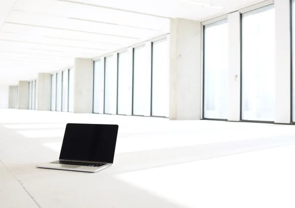Ноутбук на полу нового пустого офиса — стоковое фото
