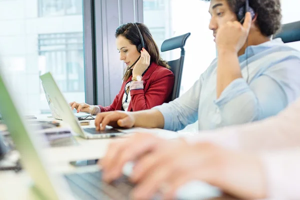 Jonge zakenvrouw met behulp van de headset en laptop — Stockfoto