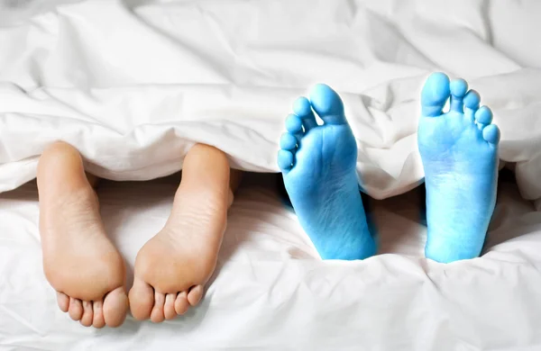 Bare feet of couple lying in bed. — Stock Photo, Image