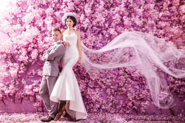 Confident wedding couple with pink flowers — Stockfoto