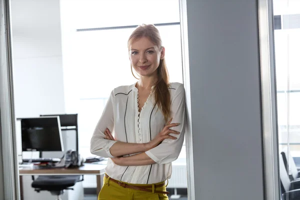 Pewna siebie bizneswoman stojąca z bronią skrzyżowana — Zdjęcie stockowe