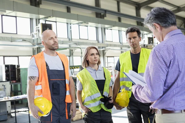 Inspector examinando expediente por los trabajadores manuales — Foto de Stock