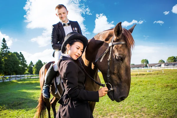 Женщина, стоящая рядом с мужчиной и сидящая на лошади — стоковое фото