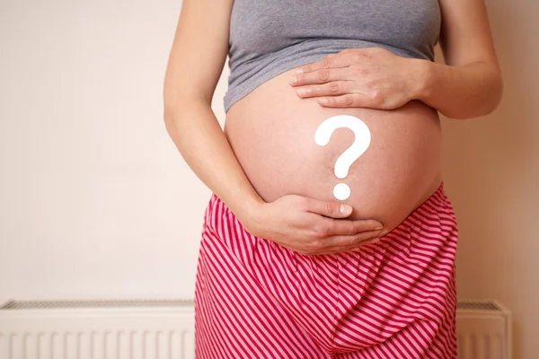 Беременная женщина с вопросительным знаком на животе — стоковое фото