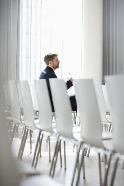 Businessman sitting in seminar hall — Stock Photo, Image
