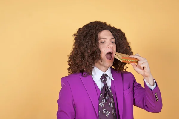 Man with afro eating sandwich — Stockfoto