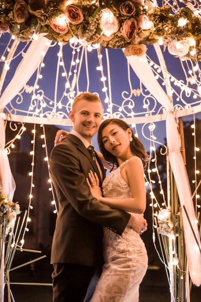 Happy couple standing in illuminated gazebo — ストック写真