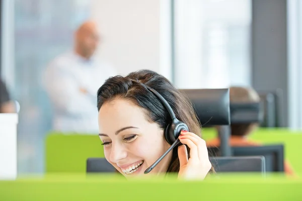 Mujer de negocios sonriente usando auriculares en la oficina — Foto de Stock