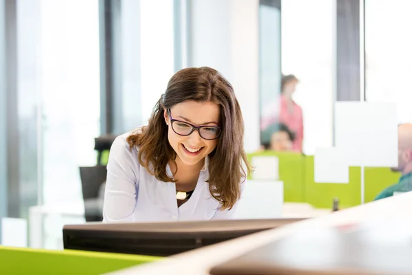 Mulher de negócios sorrindo usando o computador no escritório — Fotografia de Stock
