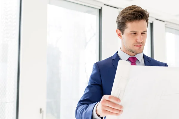 Selbstbewusster Geschäftsmann liest Blaupause — Stockfoto