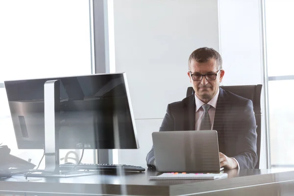 Зрілий бізнесмен використовує ноутбук в офісі — стокове фото