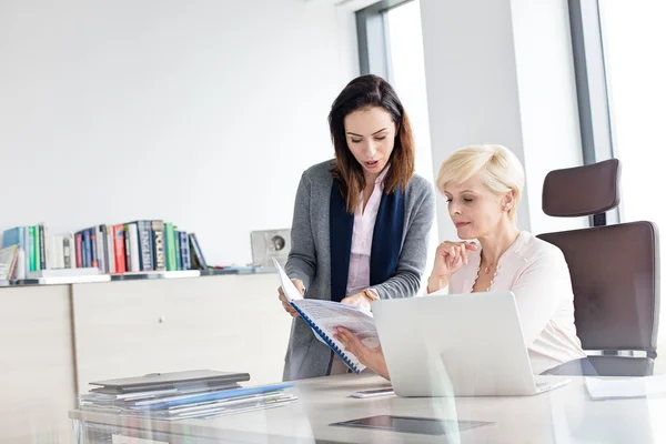 Affärskvinnor läser bok på skrivbord i office — Stockfoto