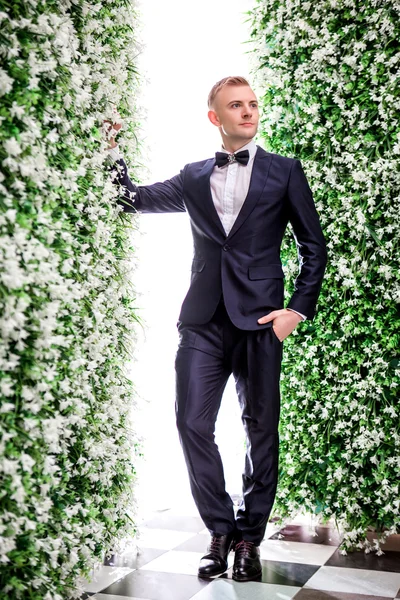 Bridegroom standing amidst flower decorations — Stock Photo, Image