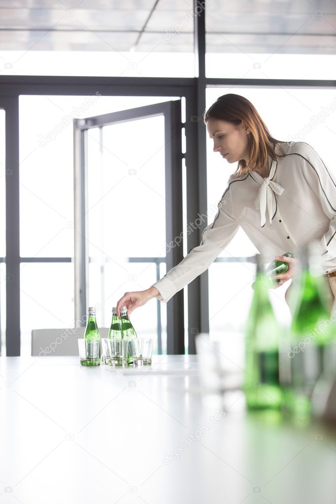 Businesswoman arranging water bottles on table