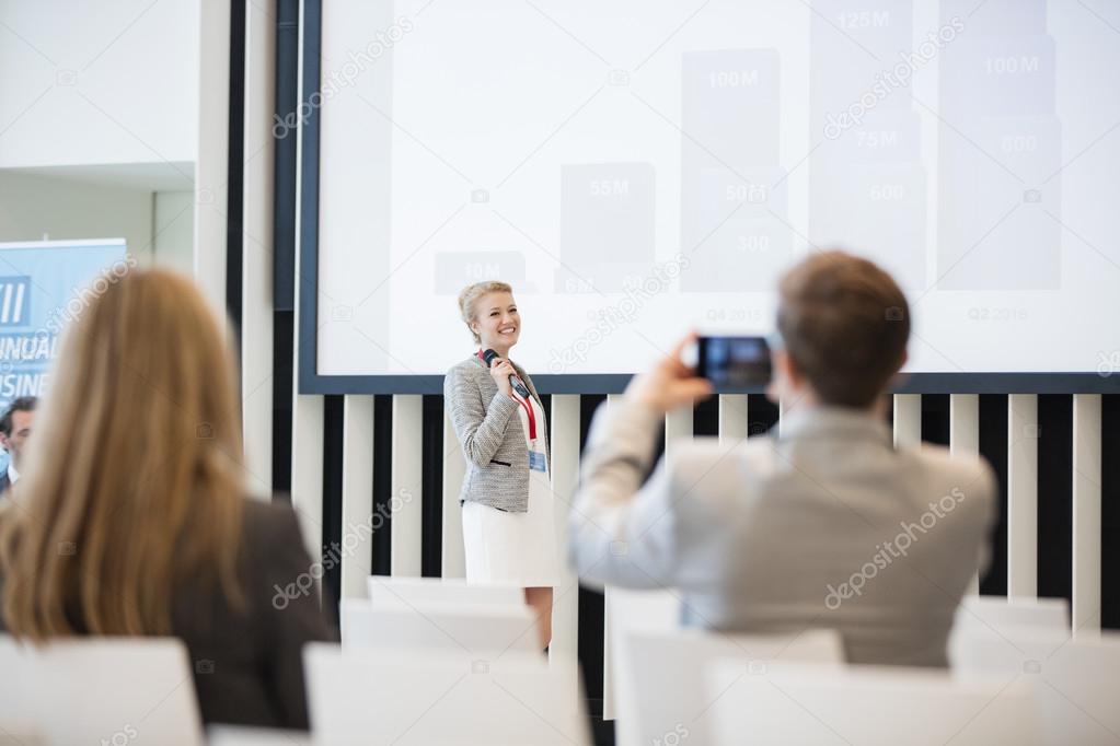 businessman photographing public speaker