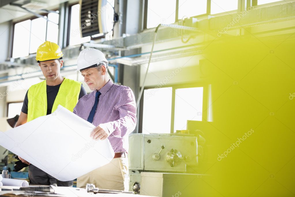 architect and manual worker examining blueprint