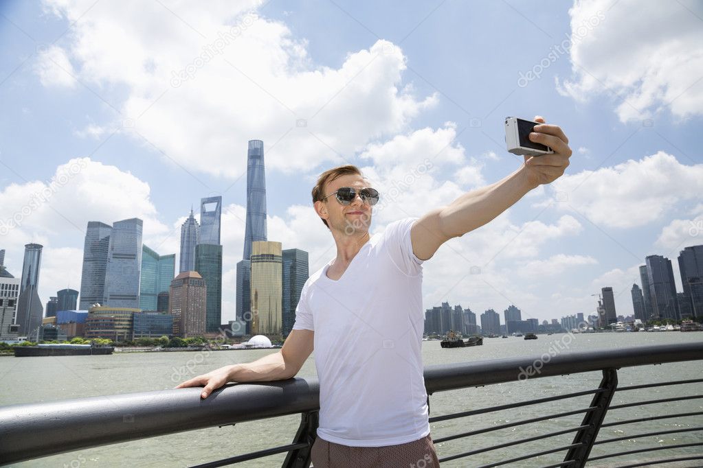 Man taking selfie against Pudong skyline 