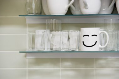 Raf üzerinde smiley işareti olan kupa