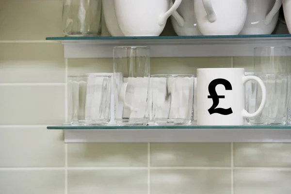 Cup on shelf with pound symbol — Stock Photo, Image