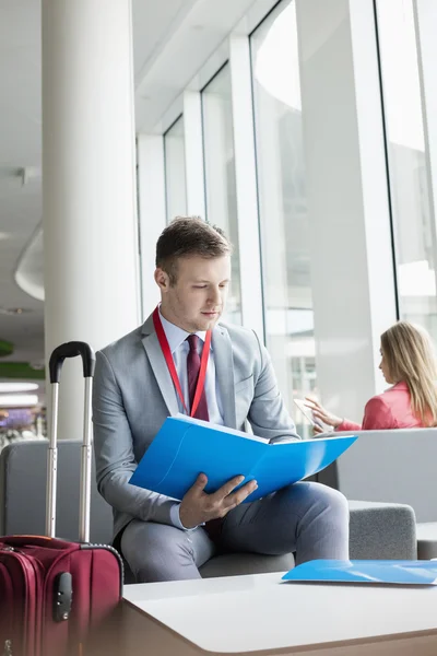 Empresario leyendo archivo mientras está sentado en el vestíbulo — Foto de Stock