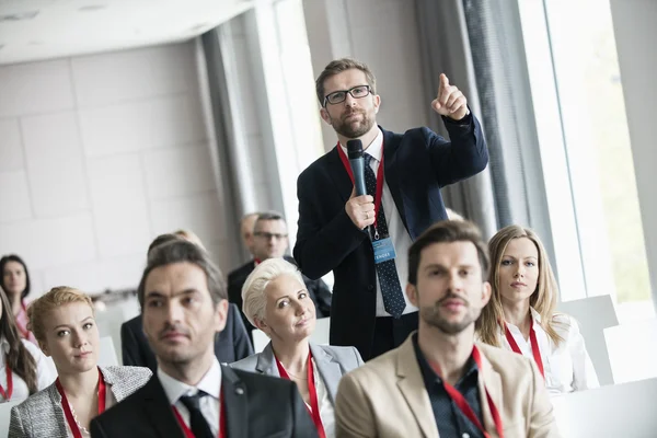 Businessman gesturing while asking question during seminar — Stock Photo, Image