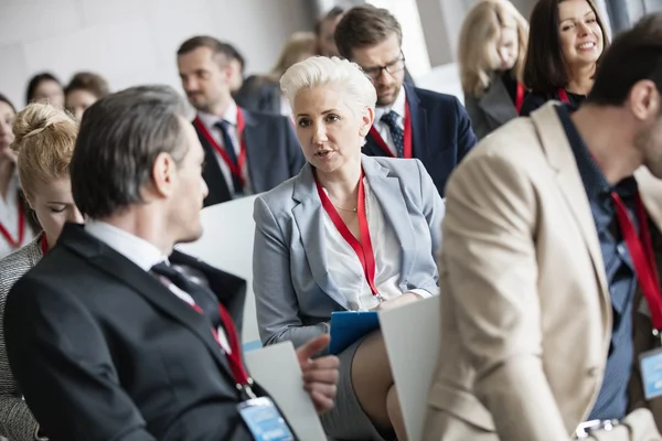 Businessman talking to businesswoman at convention center — Stock Photo, Image