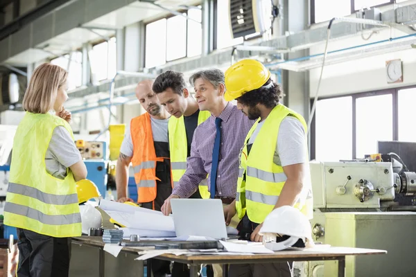 Arquitecto y trabajadores manuales examinando el proyecto — Foto de Stock