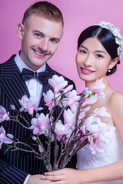 Pareja de boda sosteniendo flores artificiales — Foto de Stock