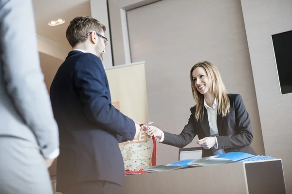 Recepcionista dando bilhete de identidade ao empresário — Fotografia de Stock