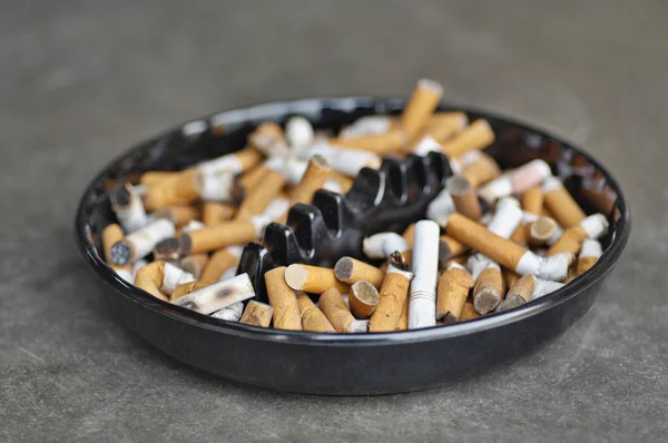 Cenicero lleno de cigarrillos en la mesa —  Fotos de Stock