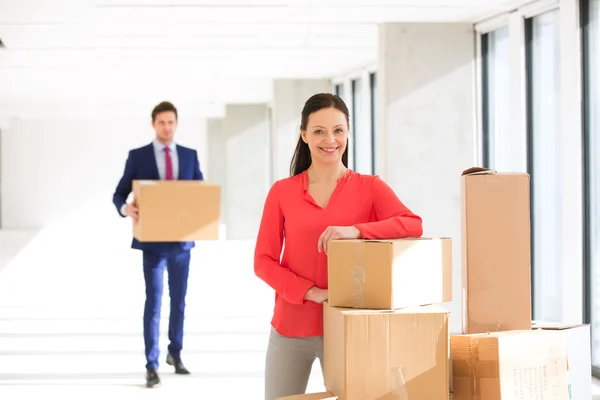 Businesswoman standing by stacked boxes with colleague — Stock Photo, Image