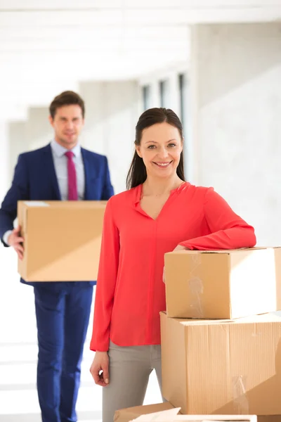 Mujer de negocios de pie junto a cajas apiladas con colega — Foto de Stock