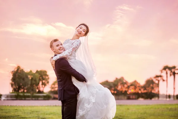 Happy groom carrying bride on field — ストック写真