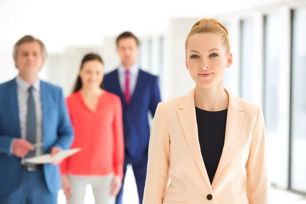 Businesswoman with team in background at office — Stock Photo, Image