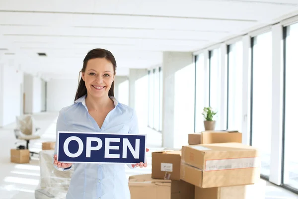 Mujer de negocios sonriente sosteniendo cartel abierto — Foto de Stock