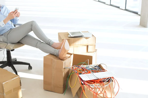 Businesswoman with feet up on cardboard box — Stock Photo, Image
