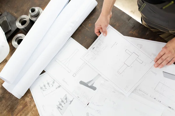 Mid adult architect with blueprints at table in industry — Stock Photo, Image